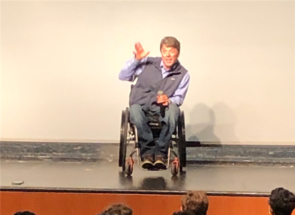 Scott Chesney (in wheelchair) on a stage shares his story.